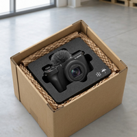 A top-down view shows the V1 camera protected by custom foam inserts within a cardboard shipping box.