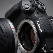 Canon EOS R100 camera with lens on a dark background