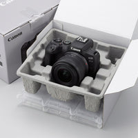An unboxing scene shows the Canon EOS R50 camera and RF-S18-45mm lens resting securely within protective cushioning.