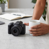 An image showing the Canon EOS R50 V lens kit beside an adult hand for scale comparison.