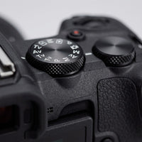 Macro close-up shot focusing on the textured control dial of the Canon EOS R50 camera.