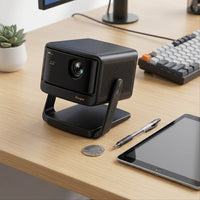 A scale-reference shot showing the compact Dangbei 4K projector next to a standard tablet and pen.