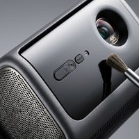 An extreme close-up photograph showcasing the complex multi-texture surface, the 4K Ultra HD lens detail, and the precise control buttons of the Dangbei MP1-Max projector.