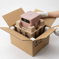 Premium Rose gold projector being safely unboxed from protective foam packaging.