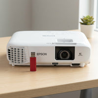 A scale reference image for an EPSON PowerLite W49 projector, positioned on a desk next to a widely recognized reference object like a standard USB stick or key fob, showing its compact size.