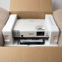 An opened cardboard box revealing the securely packed Epson PowerLite 535W short-throw projector in protective foam inserts.