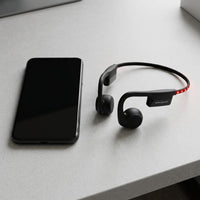 OPN Sound Dashlyte+ headphones (OS4500BL) and a black sports watch on a white desk, showing size.