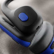 An extreme close-up of the OPN Sound Mezzo+'s earpiece, showing the textured blue button and a USB-C port against a fabric background.